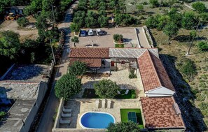 An aerial view of a residential property with a swimming pool, a patio area, and a garden.