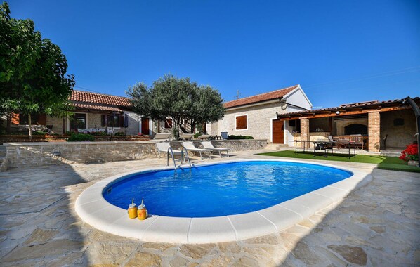 A swimming pool with lounge chairs and a stone patio.