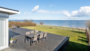 Une terrasse avec une table et des chaises donnant sur un plan d’eau.