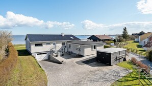 Une maison moderne avec une allée pavée, un garage et une vue sur la mer.