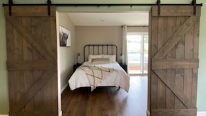 A bedroom with a bed, a nightstand, and a large sliding barn door. - A charming country escape.  Near wineries, SLO, hiking, and SM Ranch & lake. (Santa Margarita)