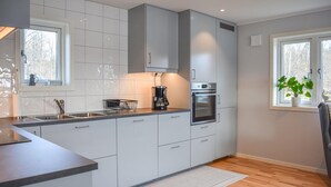 A modern kitchen with white cabinets, a built-in oven, and a coffee maker.