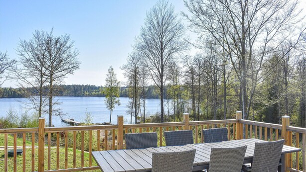 A wooden deck with a table and chairs overlooking a lake.