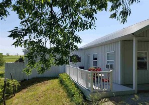 A single-story house with a porch, a fenced yard, and a clear sky. - Vineyard Cottage (Crab Orchard)