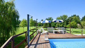 A wooden deck with a pool, lounge chairs, and umbrellas. - 4 bedroom amazing home in Pietrasanta (Pietrasanta)