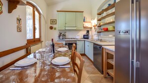 A kitchen with a dining table set for four, a refrigerator, and a microwave. - 4 bedroom amazing home in Pietrasanta (Pietrasanta)