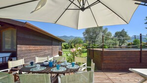 An outdoor patio with wooden furniture, a large umbrella, and a view of a garden and mountains. - 4 bedroom amazing home in Pietrasanta (Pietrasanta)