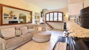 A living room with a beige sectional sofa, a large mirror, a fireplace, and a staircase leading to an upper floor. - 4 bedroom amazing home in Pietrasanta (Pietrasanta)