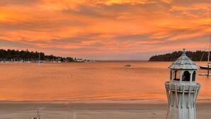 A lighthouse by a calm sea with boats and a forested island in the background. - Beachfront Home With Sweeping Views of Water and Mount Baker (Port Ludlow)