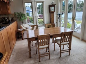 A dining area with a wooden table and chairs, a clock, and a telescope.