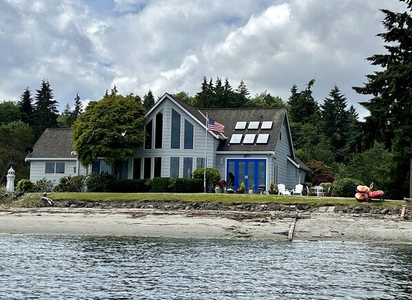 A two-story house with a blue front door and an American flag on the roof.