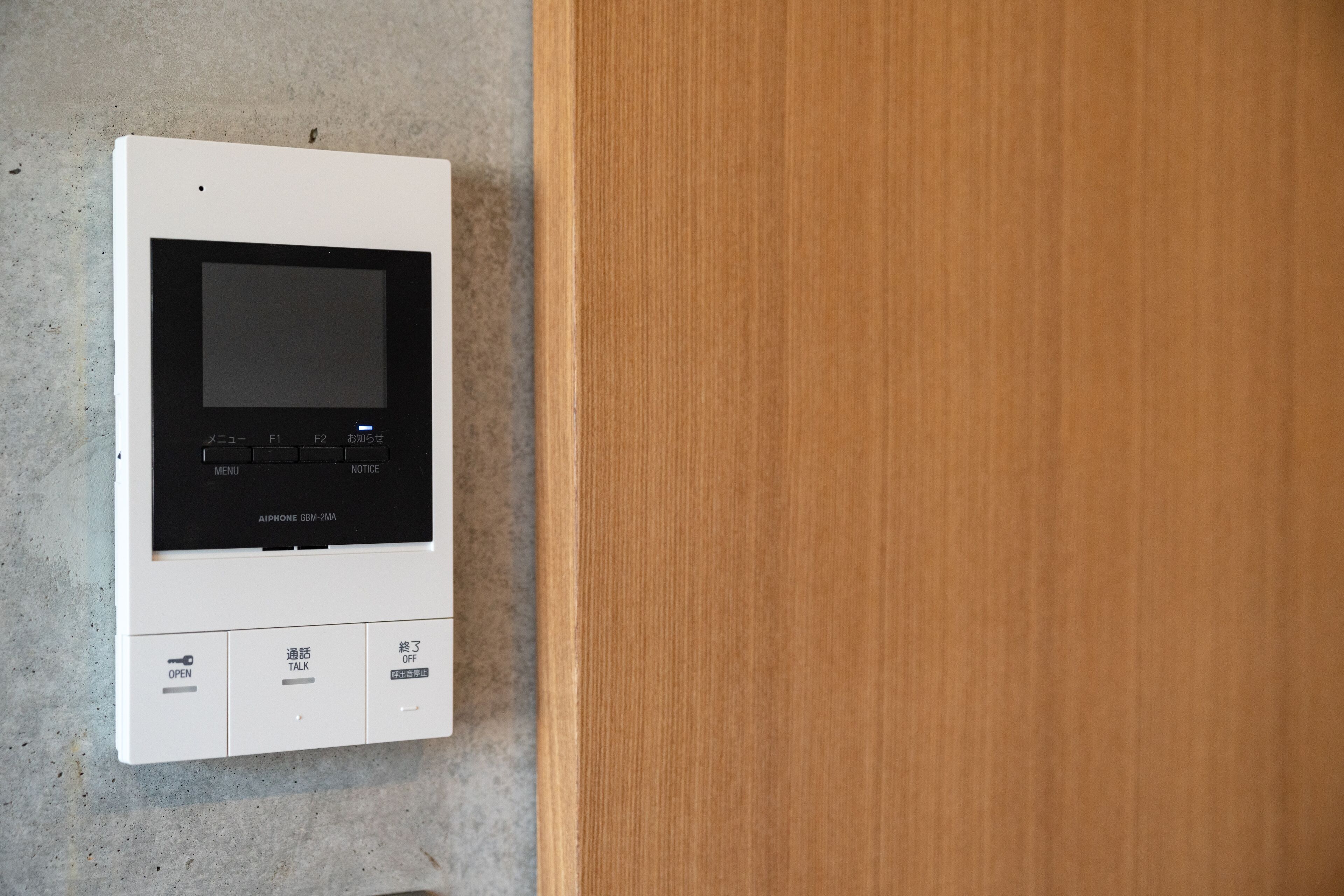 A white intercom system with a screen and buttons labeled "OPEN," "TALK," and "OFF."