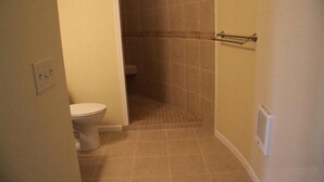 A bathroom with a toilet, a shower area, and a towel rack. - Corn Crib Cottage (Crab Orchard)