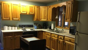 A kitchen with wooden cabinets, a stove, a sink, and a refrigerator.