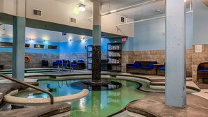 A spa area with a hot tub, seating, and a pool.