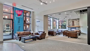 A spacious lobby with leather sofas, a fireplace, and large windows offering views of the city.
