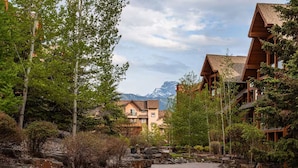 A resort with a paved walkway, wooden buildings, and a mountainous backdrop.