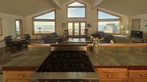 A spacious living area with a kitchen, large windows, and a view of the ocean.