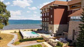 A hotel with a pool, outdoor seating, and a view of the sea. - Beachy Condo with Pool & Hot Tub (Traverse City)