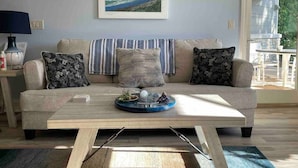 A living room with a sofa, a coffee table, and a framed picture on the wall. - Beachy Condo with Pool & Hot Tub (Traverse City)