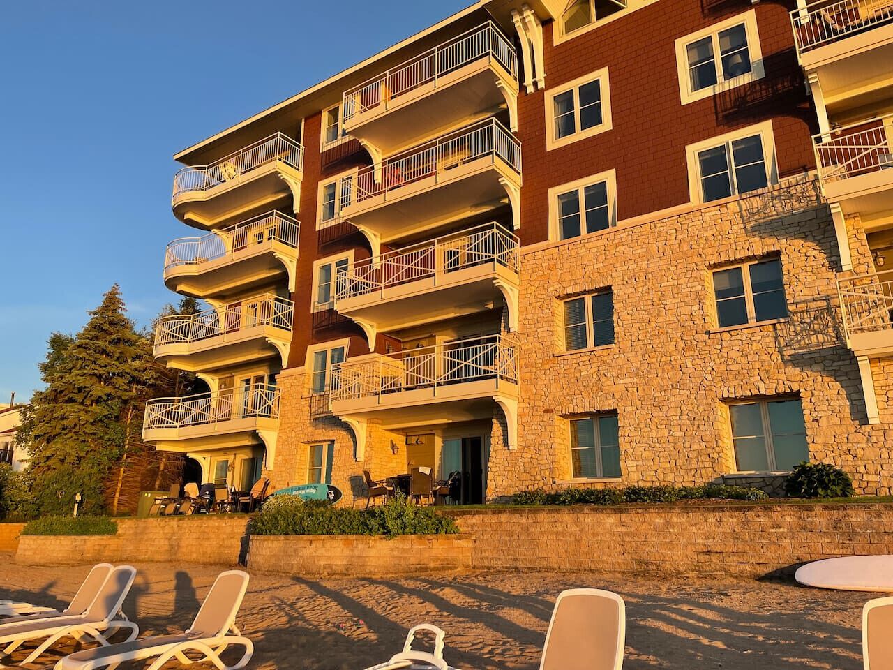 A multi-story hotel with balconies, outdoor seating, and a stone facade.