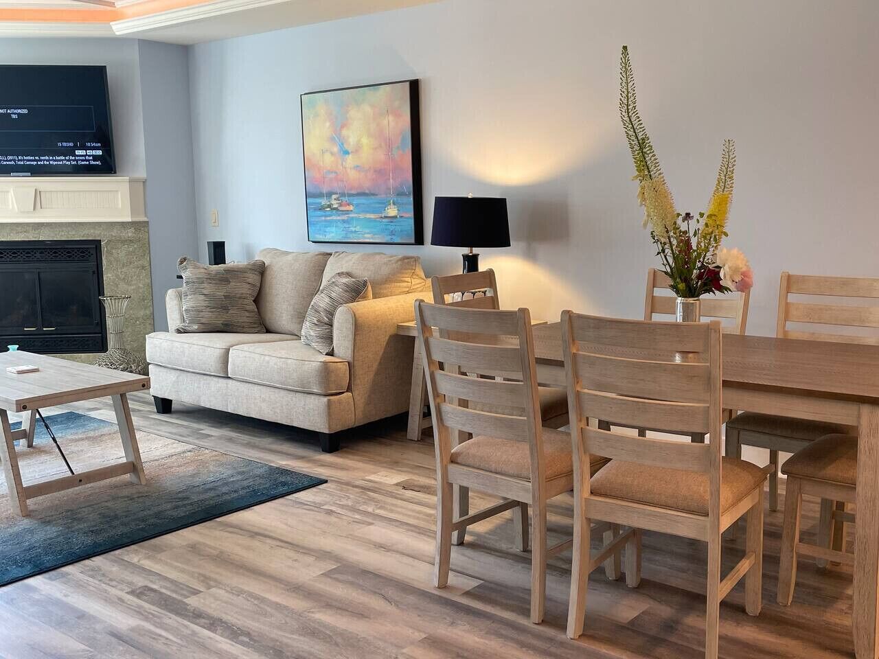 A living room with a sofa, wooden dining table, chairs, a TV, and a fireplace.