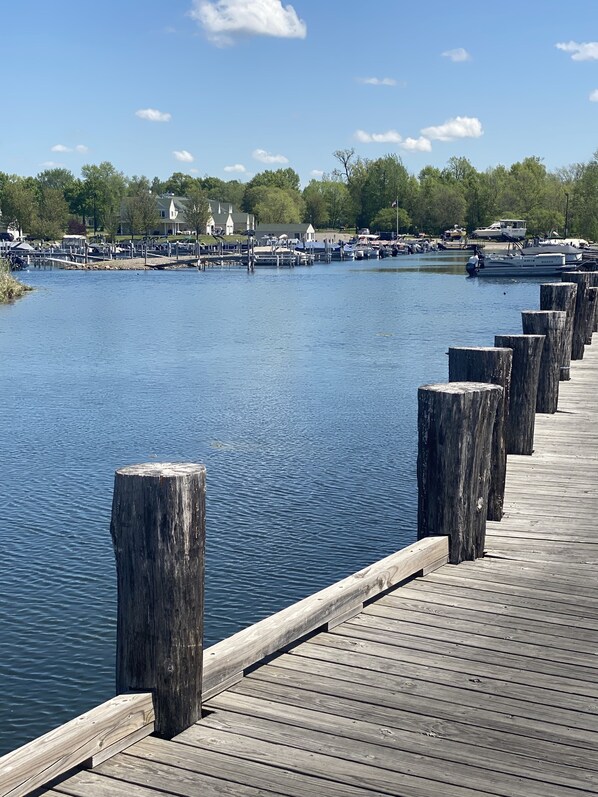 A wooden pier extending into a calm body of water with boats docked nearby.