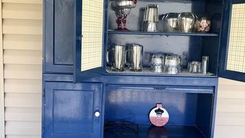 A blue cabinet with open shelves displaying various kitchenware and a decorative piece labeled "Catch of the Day."