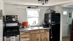 A compact kitchen with a stove, microwave, and black refrigerator. - Charming Riverside Cottage on 5 Acres- Perfect for Couples & Nature Lovers (Amherst)