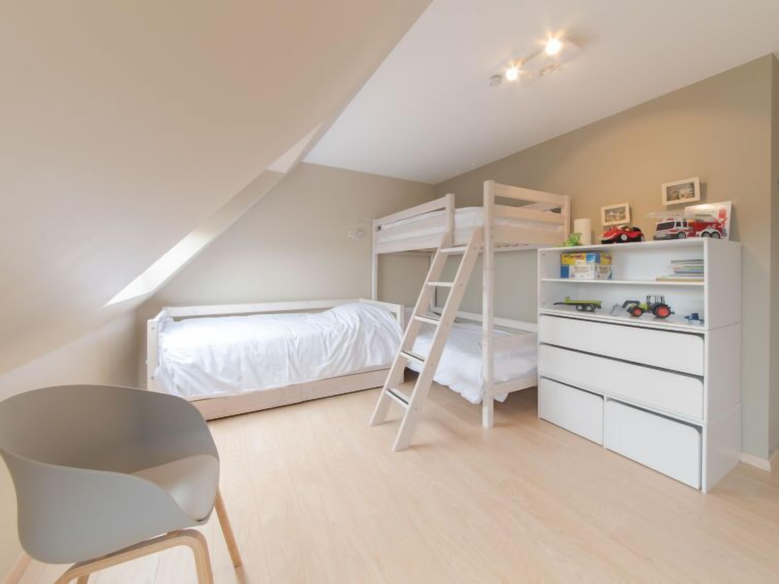 Une chambre avec des lits superposés, un bureau et une chaise.