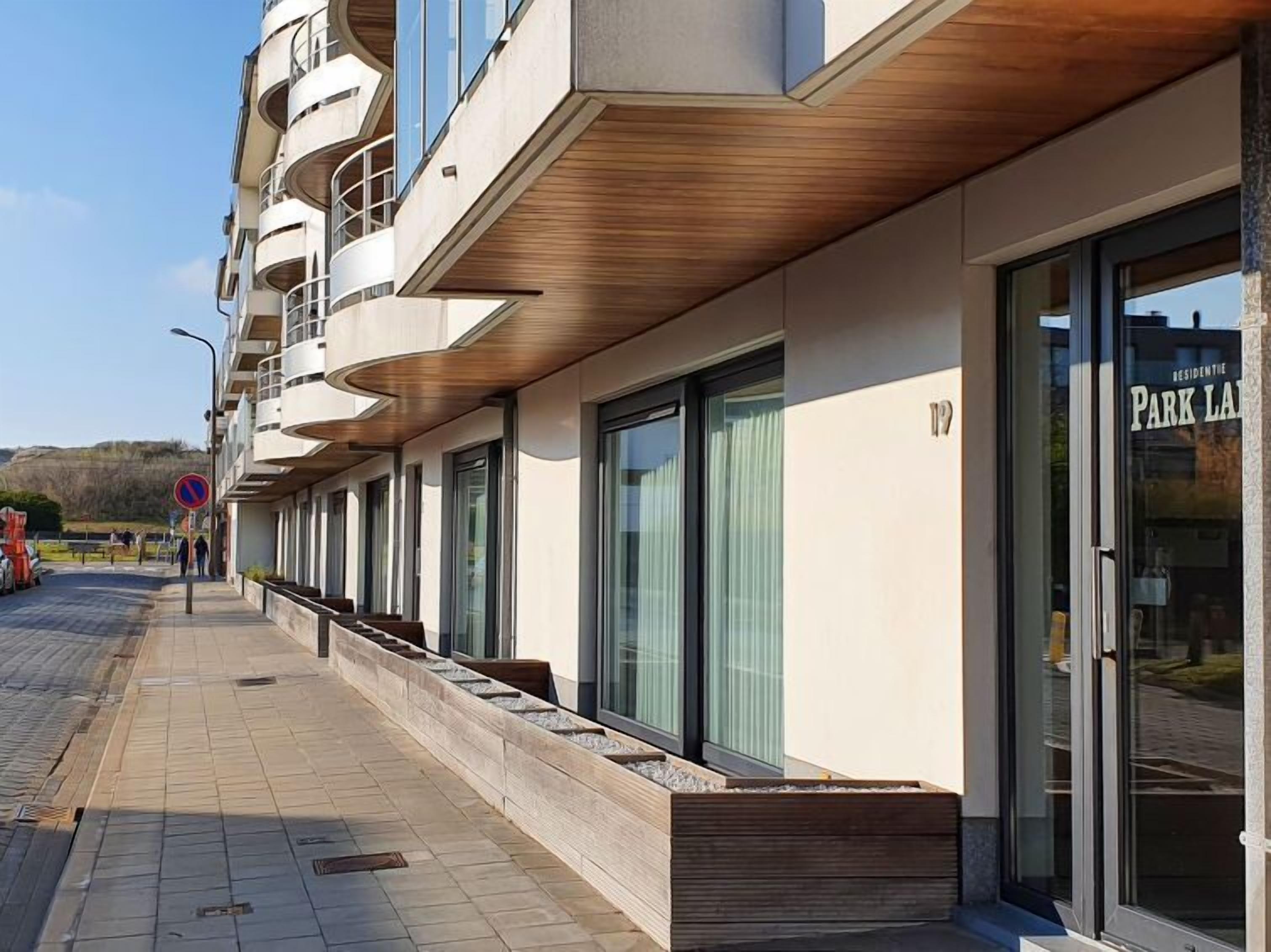 Un bâtiment moderne doté d’une façade incurvée, de grandes fenêtres et d’un auvent en bois.