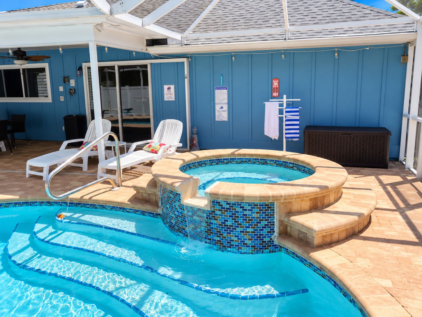 Ein Pool mit Whirlpool, Liegestühlen und einer überdachten Terrasse.