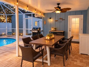 An outdoor patio with a pool, dining table, chairs, and a ceiling fan. - Heated Pool + Hot Tub, Game Garage & Teen Shed – 4BR Near Beaches (Bradenton)