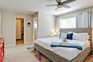 Ein Schlafzimmer mit einem großen Bett, einem Deckenventilator und Blick ins Freie durch ein Fenster.