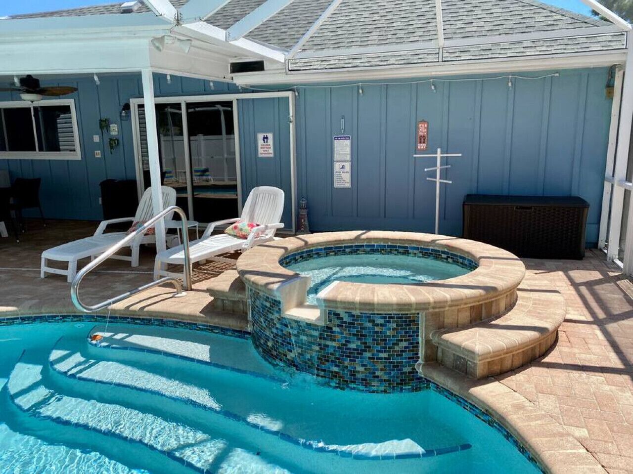 Piscina con jacuzzi, sillas de descanso y una zona de terraza cubierta.