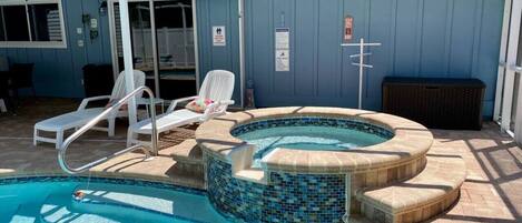 Piscina con jacuzzi, sillas de descanso y una zona de terraza cubierta.