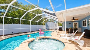 Een zwembad met een jacuzzi, ligbedden en een overdekt terras.