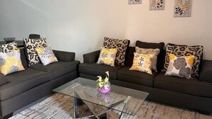 Sala de estar com sofá modular, mesa de centro de vidro e almofadas decorativas.