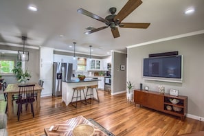 A modern kitchen with a central island, wooden dining table, and bar stools. - Momma's House On Landa Dt 430 3 Bedroom Home by RedAwning (New Braunfels)