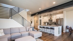Una cocina moderna con una isla central, taburetes de bar y un refrigerador de acero inoxidable.