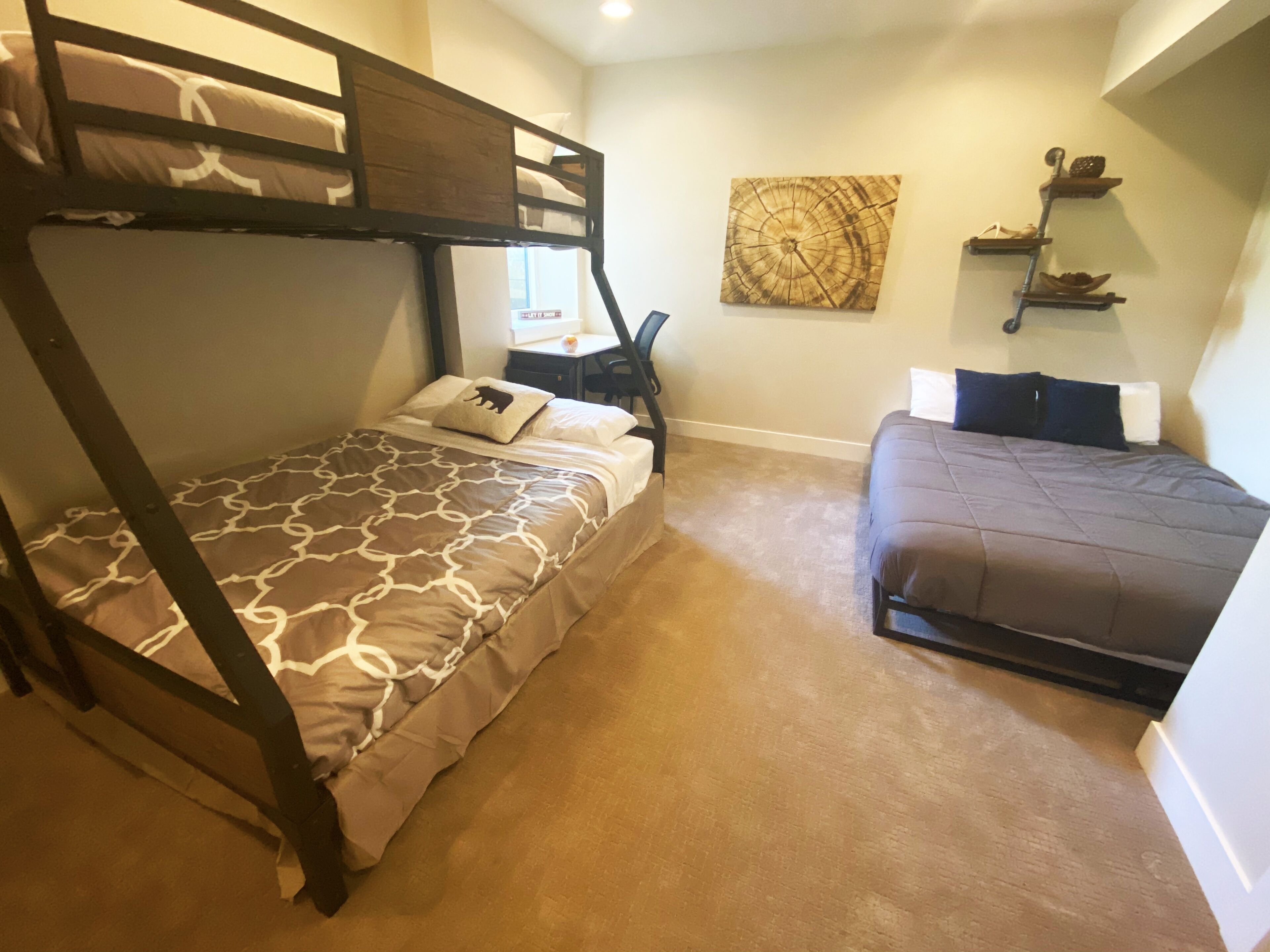 A room with two bunk beds, a desk, and a wall-mounted shelf.