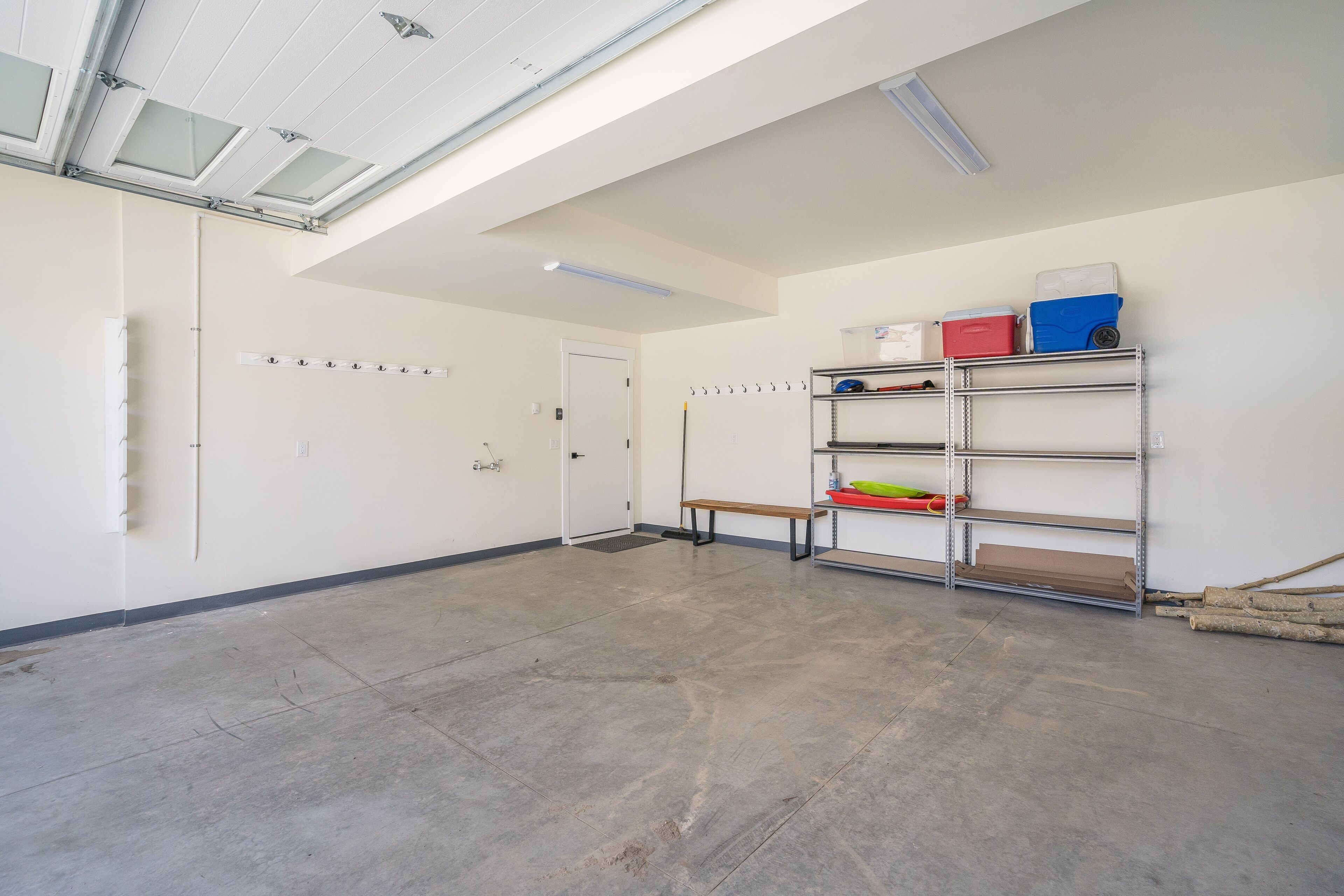 A spacious room with a high ceiling, skylight, and a metal shelving unit against the wall.