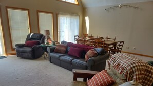 A spacious living room with a leather sofa, a dining table, and a patterned bed. - Knotty Knob is your mountain get away! (Frametown)