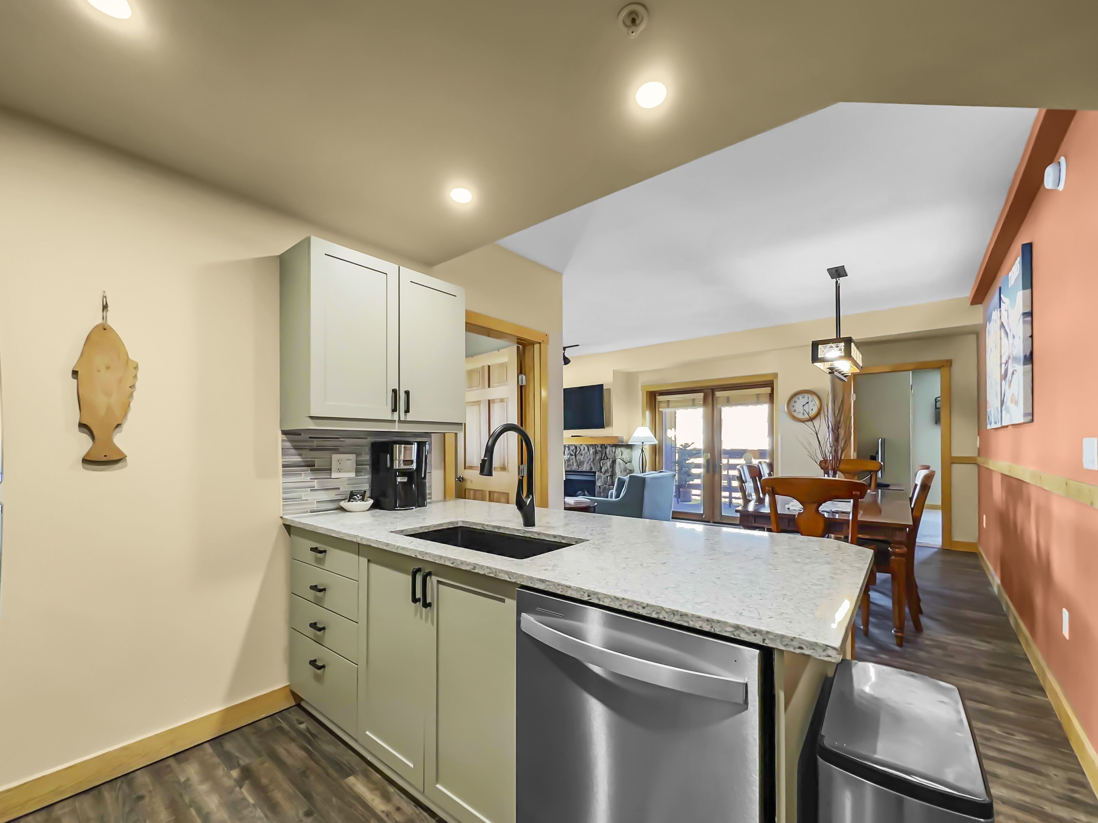 A modern kitchen with a built-in dishwasher, a coffee maker, and a sink.
