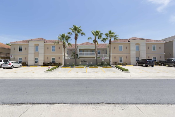 A multi-story hotel with a parking lot in front.