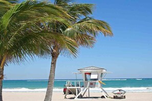 A lifeguard tower on a beach with a clear view of the ocean and a palm tree. - Modern Golf  Beach villa 2 -Between Boca Raton & Deerfield Beach (Deerfield Beach)
