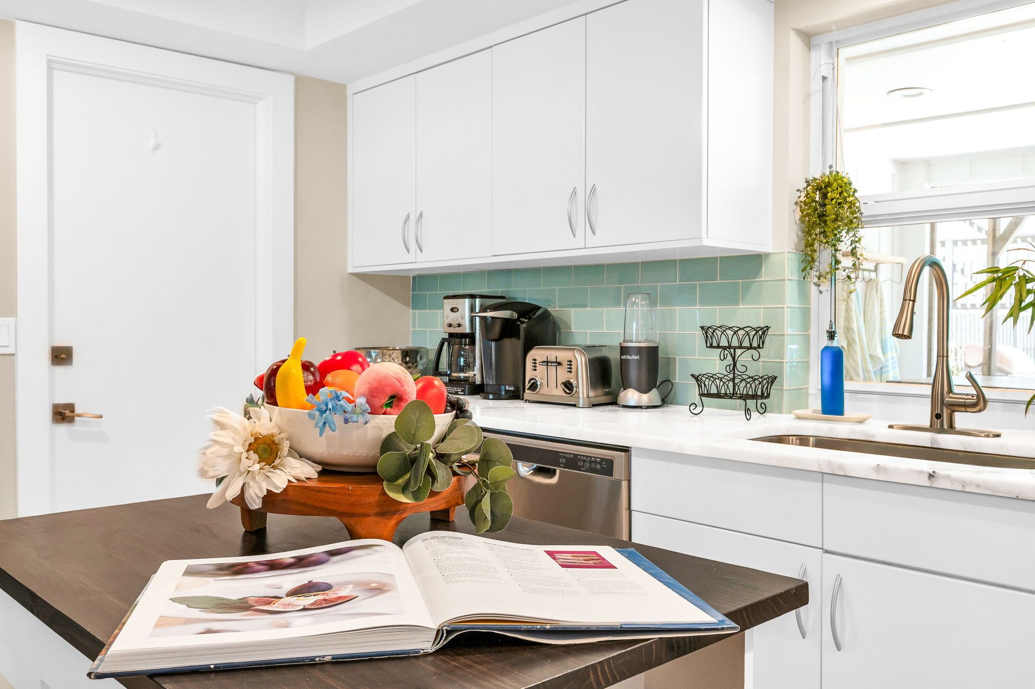 A modern kitchen with white cabinets, a coffee maker, a toaster, and a sink.