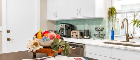 A modern kitchen with white cabinets, a coffee maker, a toaster, and a sink.