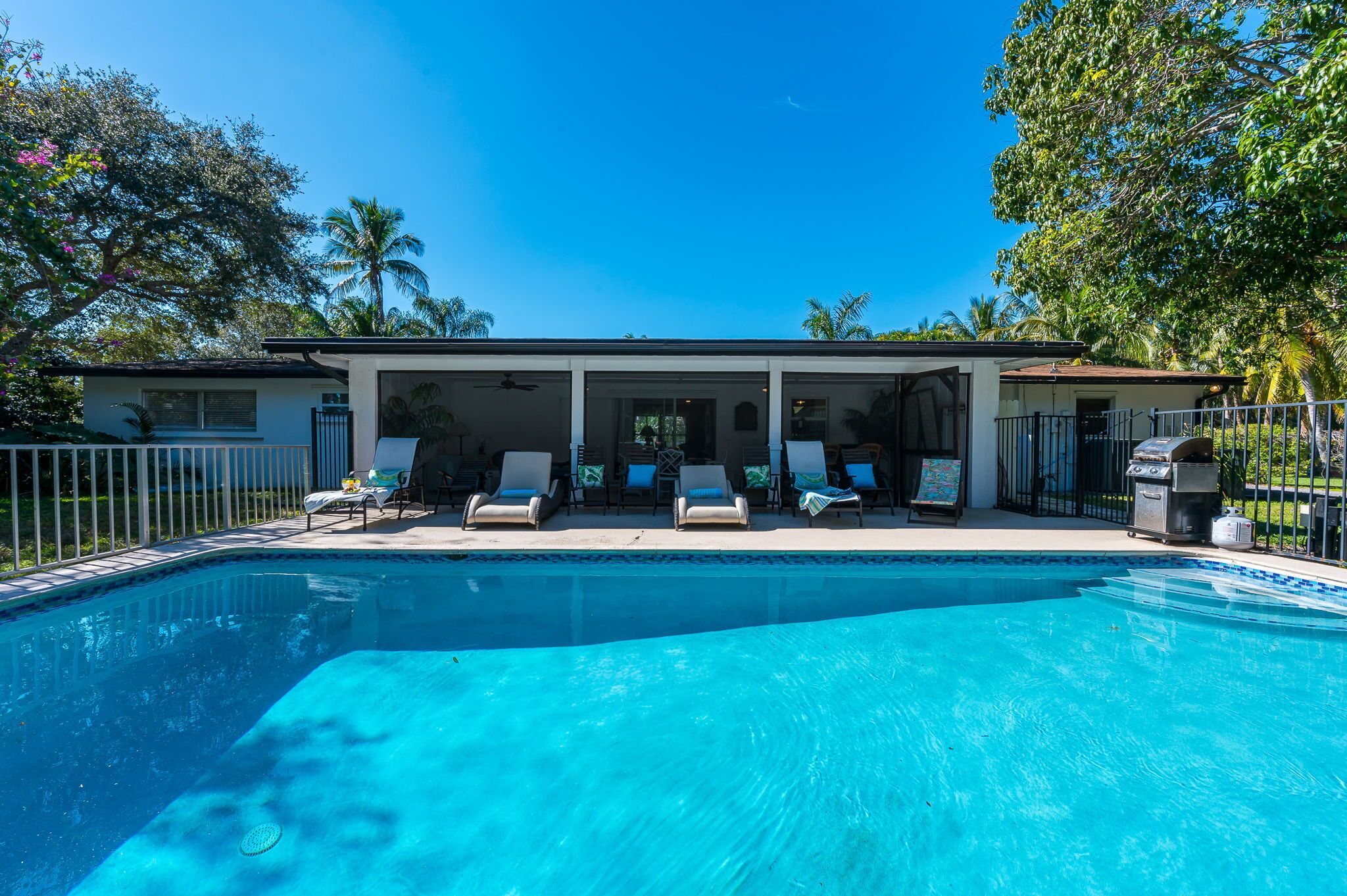 A swimming pool with lounge chairs and a covered patio area.