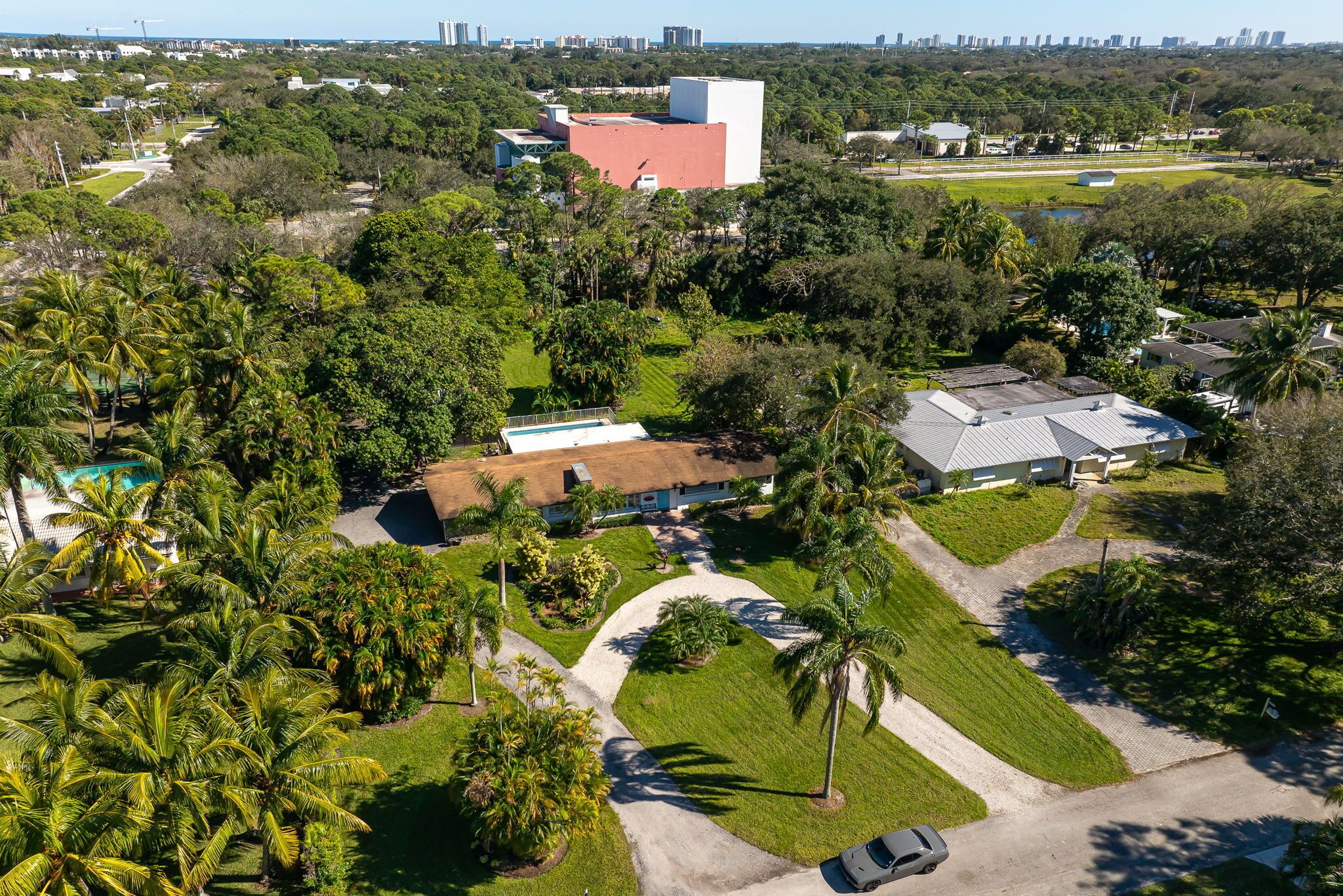 An aerial view of a residential area with houses, a swimming pool, and palm trees.